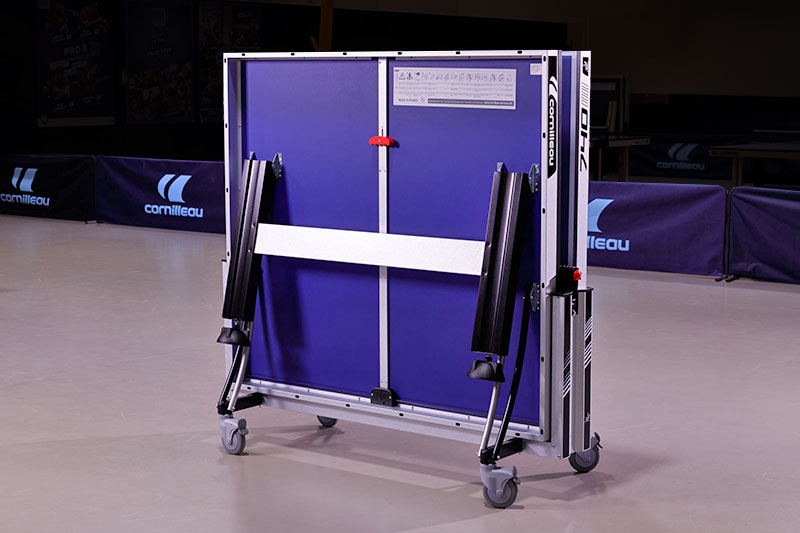 main qui range une balle dans le flanc d'une table de ping pong Cornilleau 500 indoor